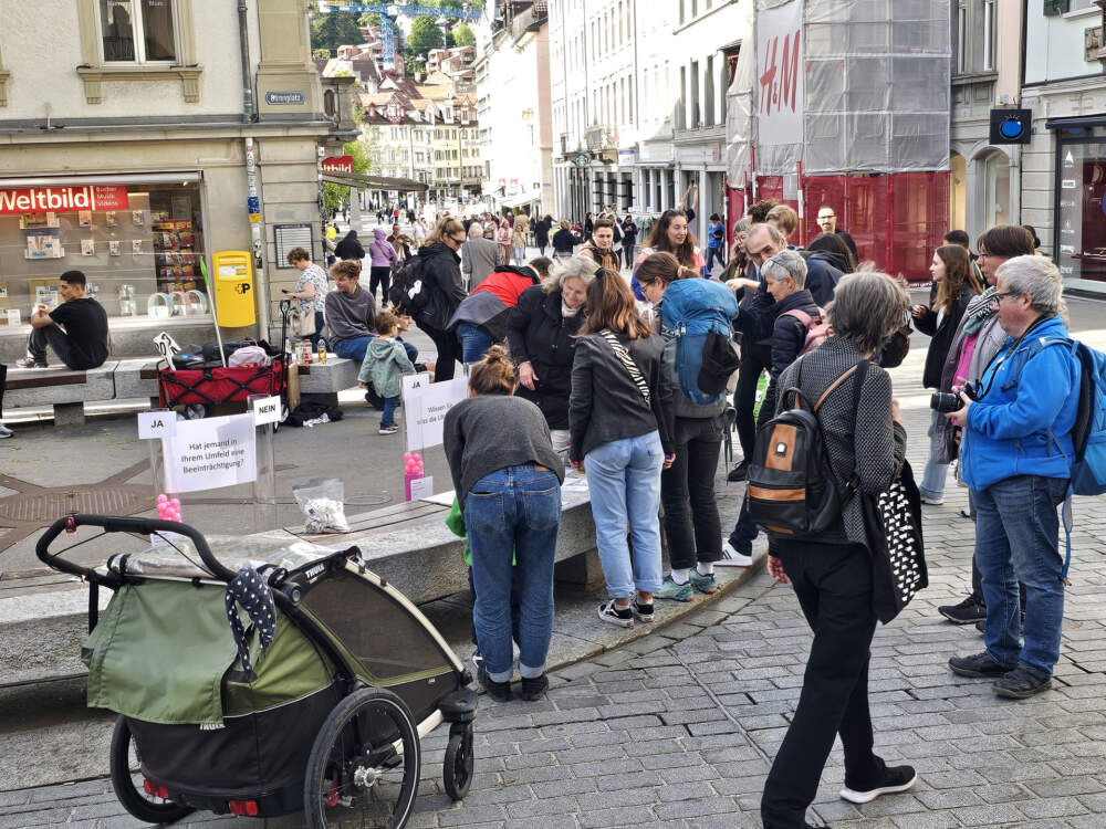 Viele Leute stehen bei Umfragometer. Sie sprechen miteinander. Und sie werfen B&auml;lle als Antwort in eine Plexiglasr&ouml;hre.