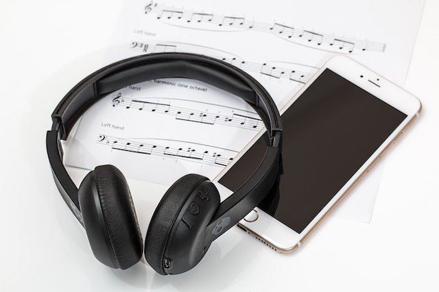 Ein Kopfh&ouml;rer liegt neben einem Smartphone. Sie sind nicht &uuml;ber Bluetooth und nicht &uuml;ber ein Kabel verbunden.
