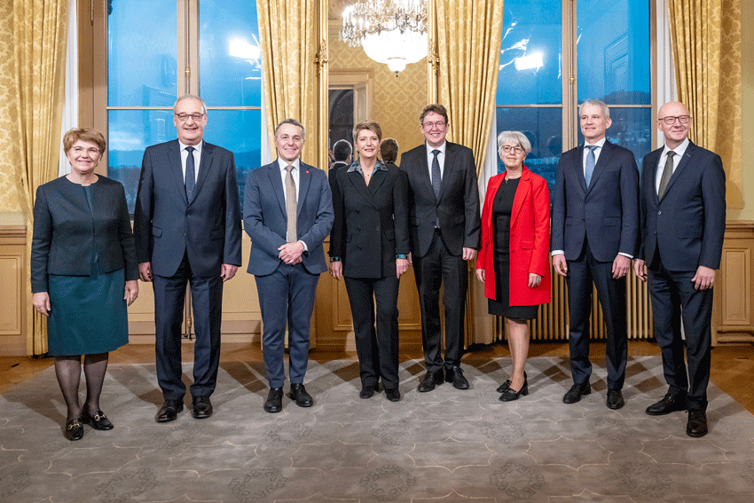 Die Bundesr&auml;tinnen und Bundesr&auml;te stehen in einer Reihe nebeneinander. Von links nach rechts: Viola Amherd, Guy Parmelin, Ignazio Cassis, Karin Keller-Sutter, Albert R&ouml;sti, Elisabeht Baume-Schneider und Beat Jans. Rechts von Beat Jans steht der neue Bundeskanzler Viktor Rossi.
