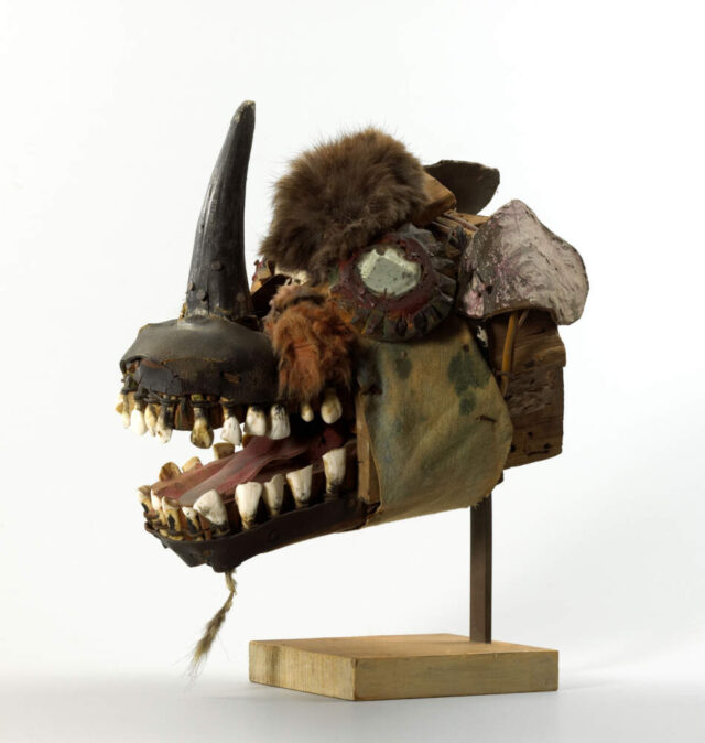 Eine Skulptur von einem Fantasiekopf mit einem Horn auf der Nase und mit offenen Mund, in dem man die Z&auml;hne sieht.