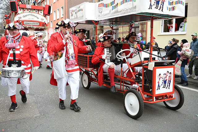 Eine Fasnachtsgruppe mit einem Fasnachtswagen. Sie tragen rote Fr&auml;cke und einen Napoleon-Hut.