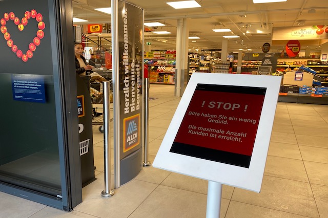 Der Monitor am Eingang steht auf Rot. Dann steht: Stopp. Bitte haben Sie ein wenig Geduld. Die maximale Anzahl Kunden ist erreicht.