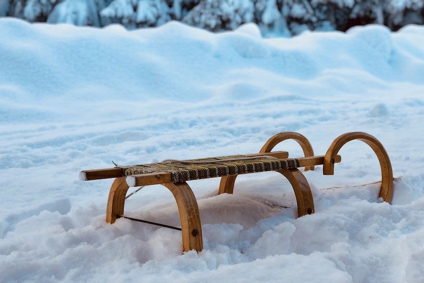 Ein Holzschlitten steckt im tiefen Schnee fest.