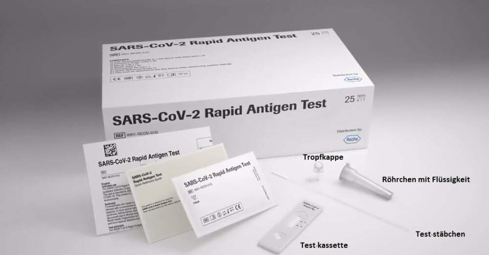 Eine Packung mit dem Selbst&middot;test von Roche. Vor der Packung liegen das R&ouml;hrchen mit Fl&uuml;ssigkeit und der passende Deckel, das Testst&auml;bchen und der Teststreifen. Daneben liegt die Anleitung.
